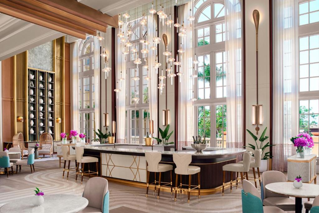 un restaurante con mesas, sillas y ventanas grandes en The Ritz-Carlton Naples en Naples