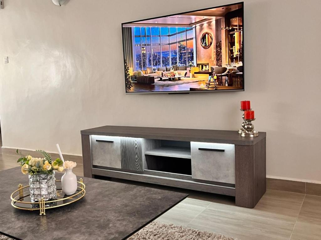 a living room with a television on a wall at Midtown Executive Suites CBD With Large Balcony in Nakuru