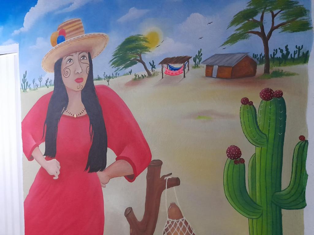 Casa Hostal Perla Roja في ريوهاتشا: لوحة لامرأة ترتدي ثوب احمر وصبار