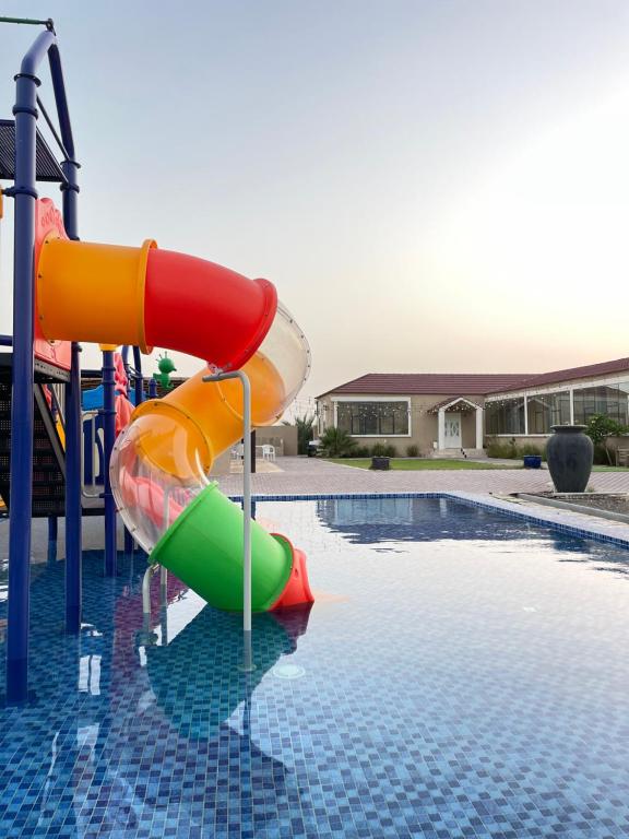 a colorful water slide next to a swimming pool at Alreef farm in Ras al Khaimah