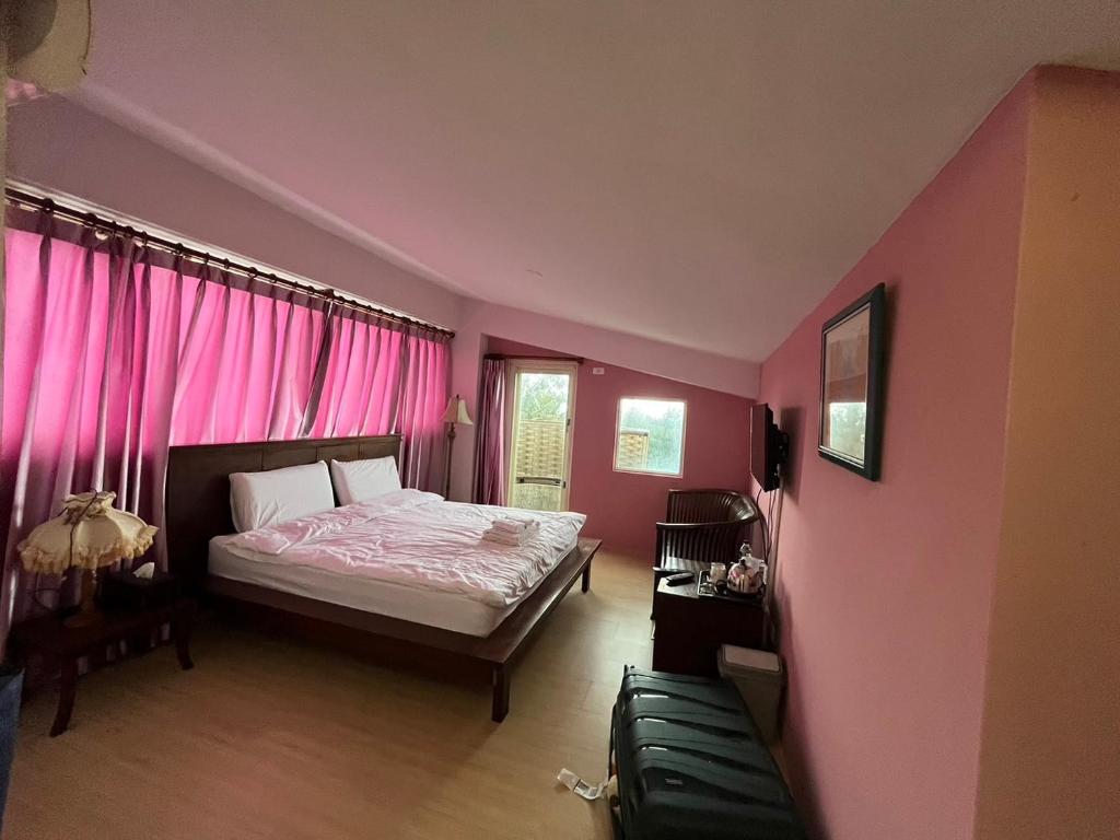 a pink bedroom with a bed and pink curtains at Hualien Bay in Ji'an