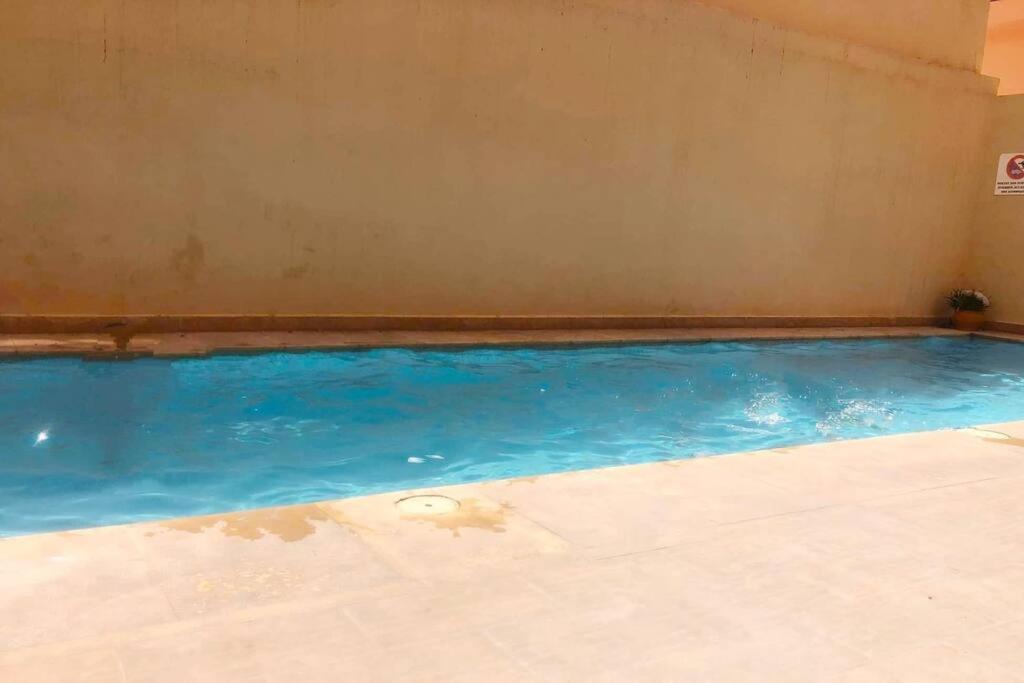 a swimming pool with blue water in a room at appartement dans résidence Marrakech avec piscine in Marrakesh