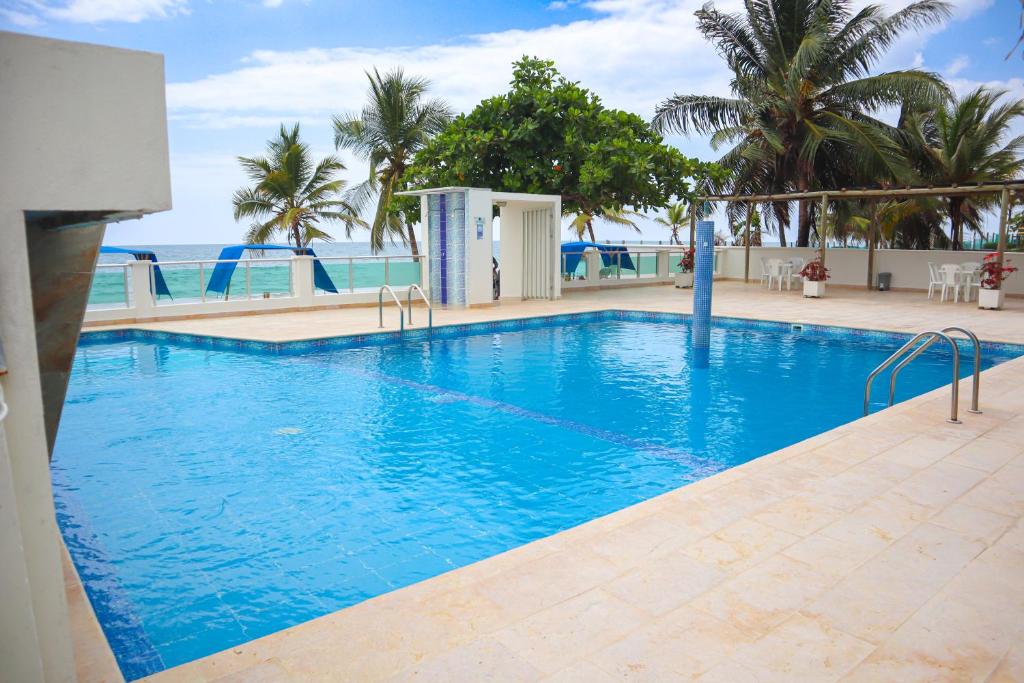 a large swimming pool with blue water and palm trees at Magico Apartamento Frente al Mar 3 Habitaciones B21 in Coveñas