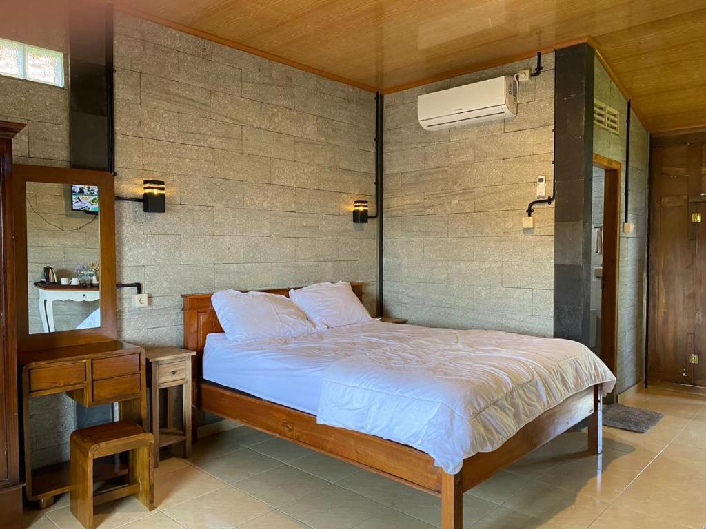 una camera con letto, tavolo e specchio di Djiwanta Cottage by Balkondes Sambirejo a Groyokan