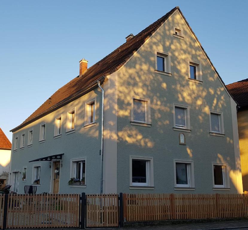 ein weißes Haus mit einem Zaun davor in der Unterkunft Ferienwohnung Nr 4 in Litzendorf