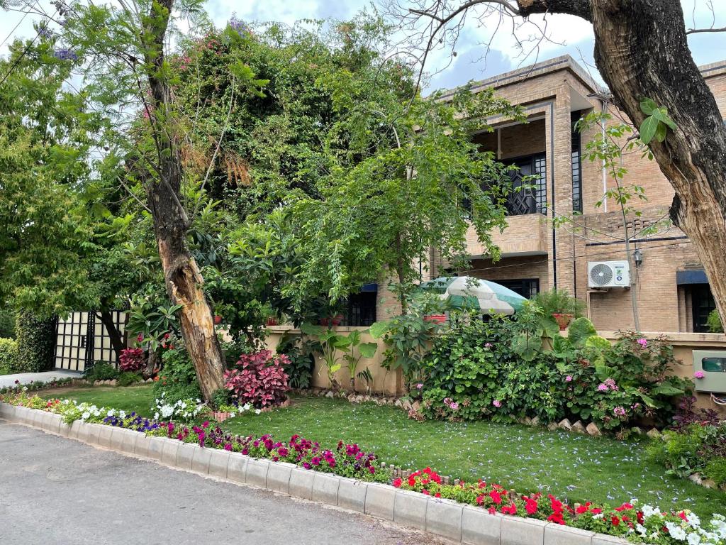 a house with a garden of flowers in front of it at Riviera Courtyard Guest House Islamabad in Islamabad