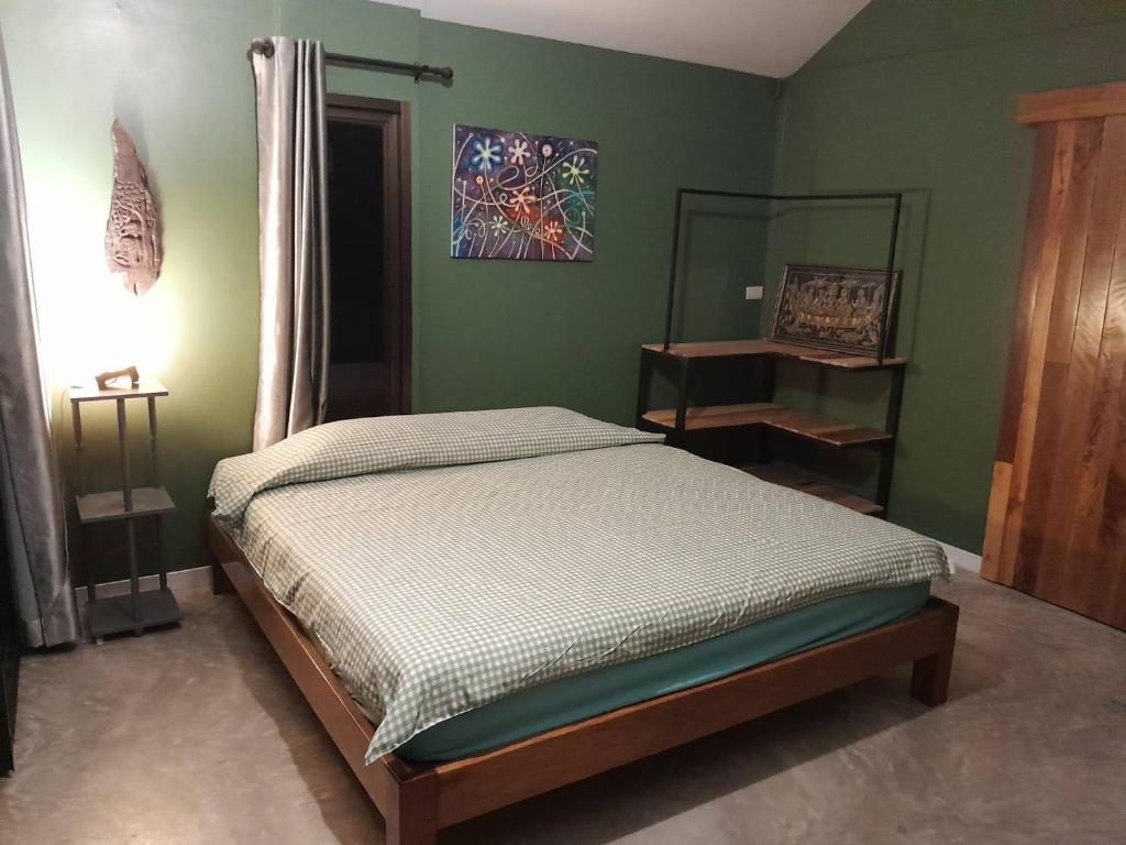 um quarto com uma cama numa parede verde em บ้านลูกจัน Bann Lookjan Trat em Trat