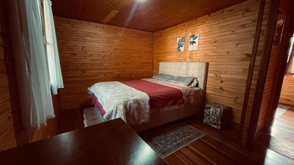 um pequeno quarto com uma cama num quarto de madeira em Chale em Atibaia em Atibaia