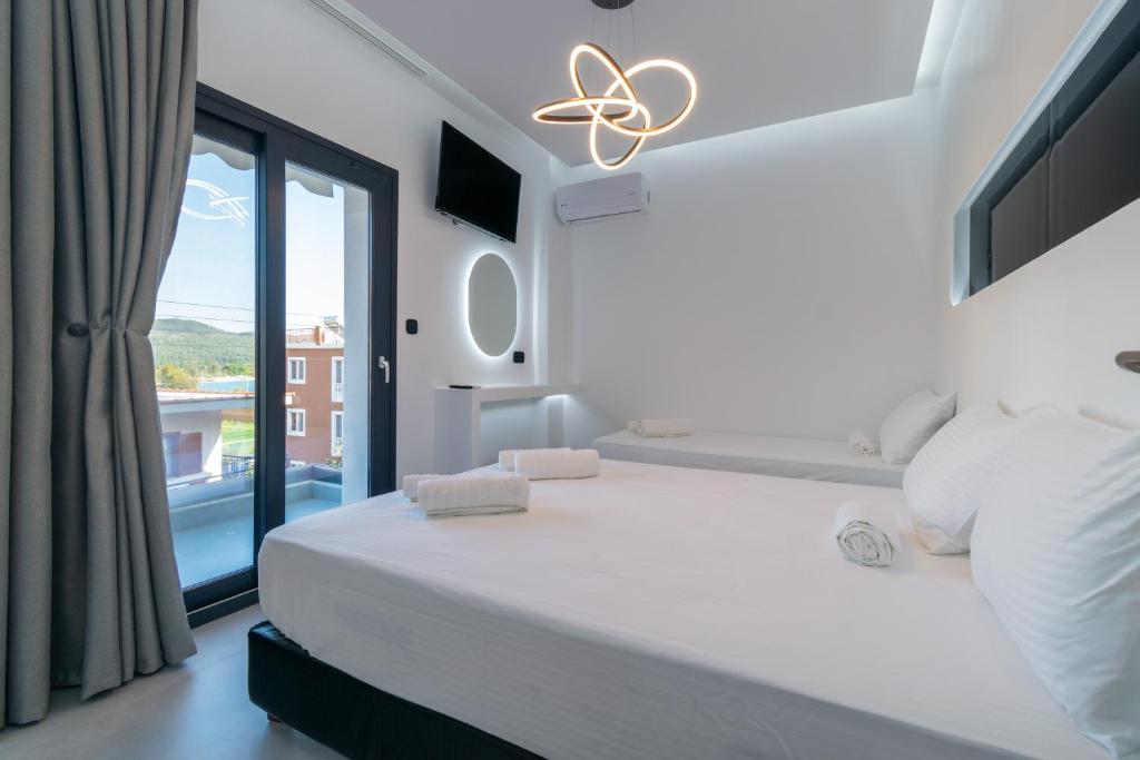 a white bedroom with a large bed and a window at SithoniaRS Luxury 1st Floor Apartment With SeaView in Neos Marmaras