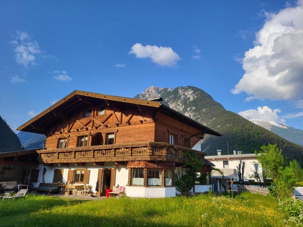 una gran casa de madera con montañas en el fondo en Ferienwohnungen Riedl en Scharnitz