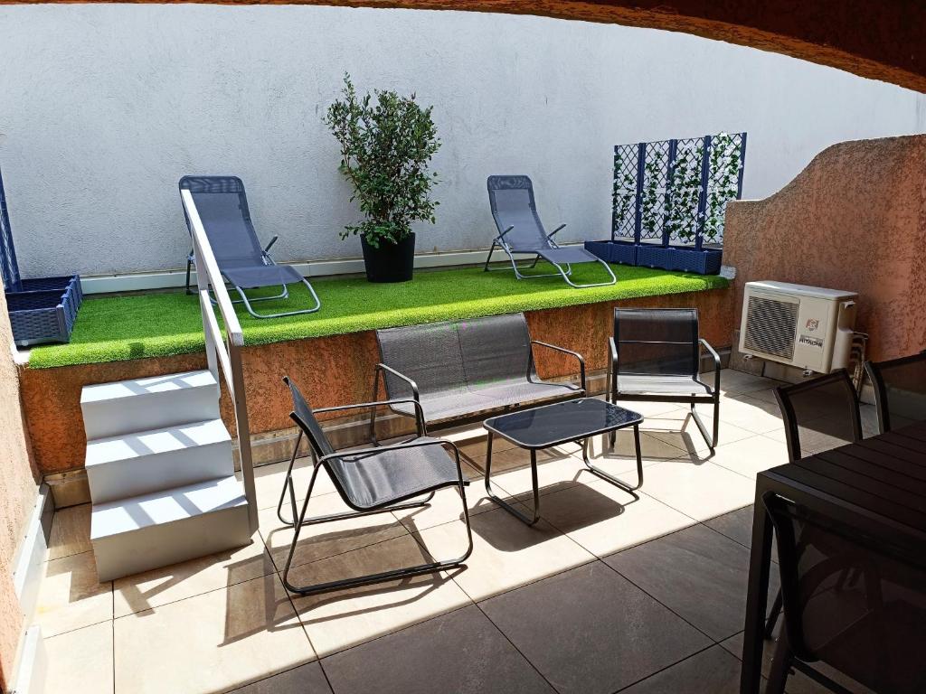 un patio avec trois chaises et une table verte dans l'établissement Appartement a 50 mètres de la plage, à Fréjus