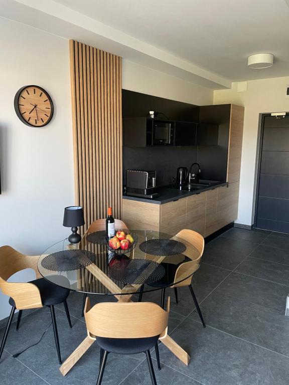 ein Esszimmer mit einem Tisch, Stühlen und einer Uhr in der Unterkunft Apartament BALTIC 1 in Jastrzębia Góra