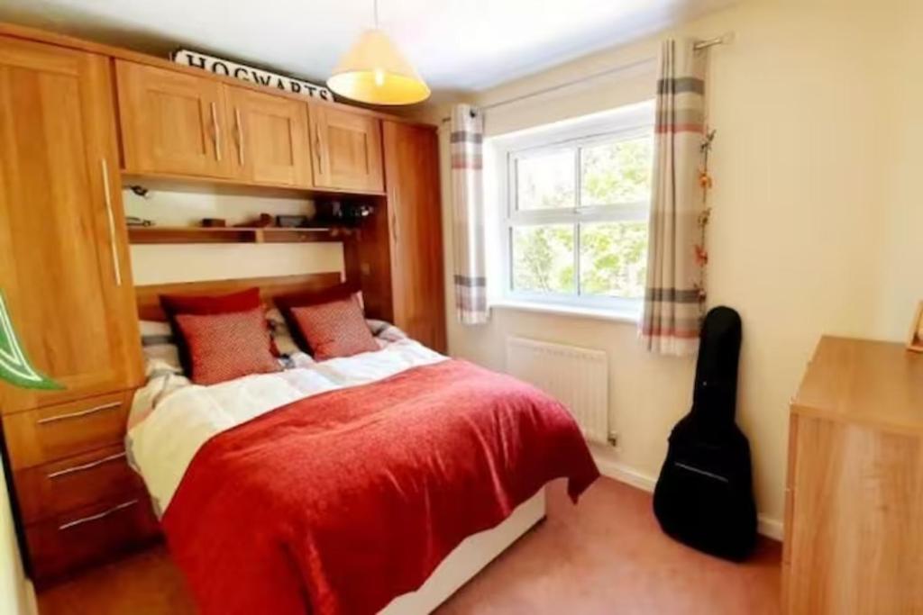 a bedroom with a bed with a red blanket and a window at 1 small double room in a cul de sac classy area in a shared house in Bristol