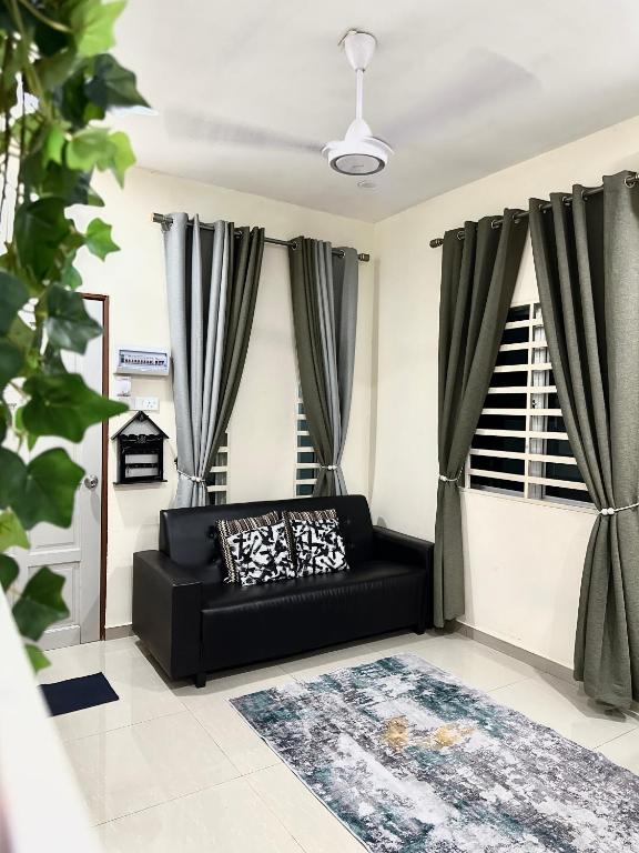 a black couch in a living room with curtains at DeAsmarra Homestay in Tanjung Piandang