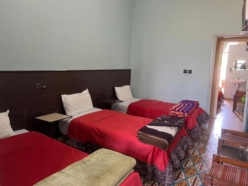 a room with three beds with red sheets at Hotel des cedres,azrou maroc in Azrou
