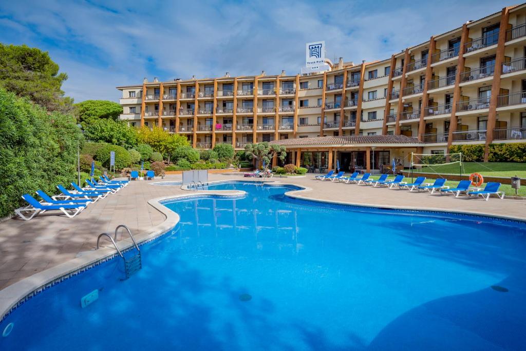 un hotel con una gran piscina y tumbonas en GHT Aparthotel Tossa Park, en Tossa de Mar