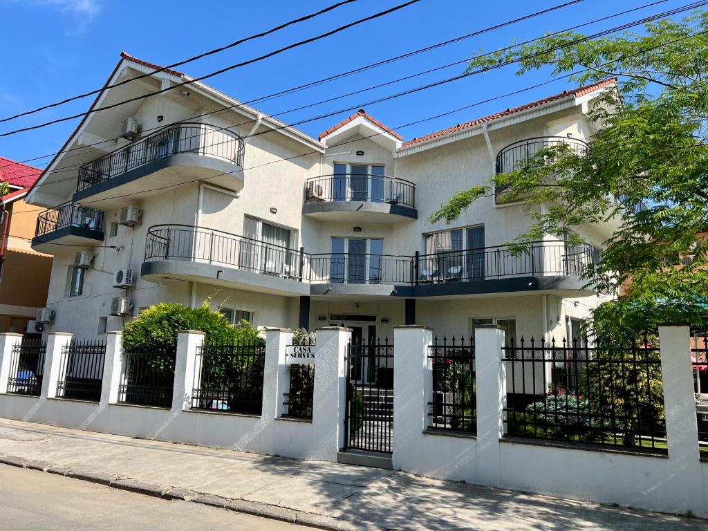 a white building with a fence in front of it at Casa Servus in Mamaia Nord