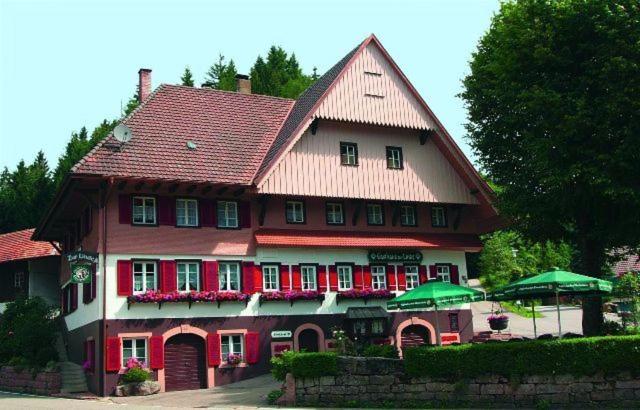 une grande maison avec un toit rouge et des parasols verts dans l'établissement Gasthaus Zur Linde, à Oberharmersbach