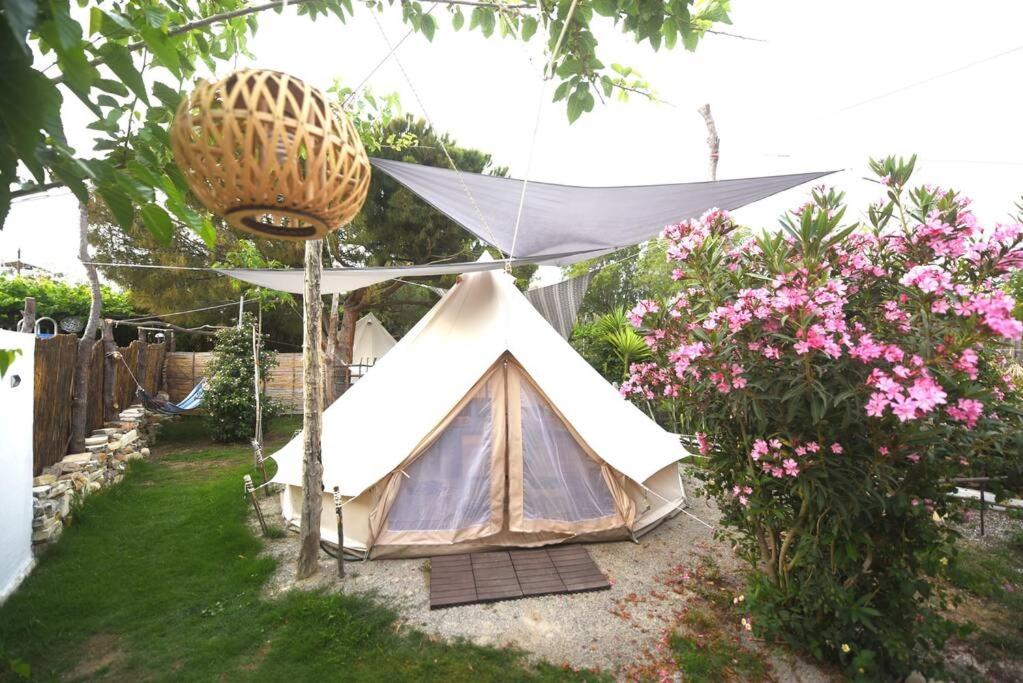 une tente blanche dans un jardin avec des fleurs roses dans l'établissement Happy Glamping 2, à Kalamaki