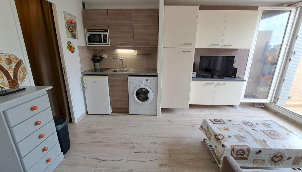 a small kitchen with white cabinets and a washer and dryer at Studio à 50 m de la plage et du sentier littoral in Hyères