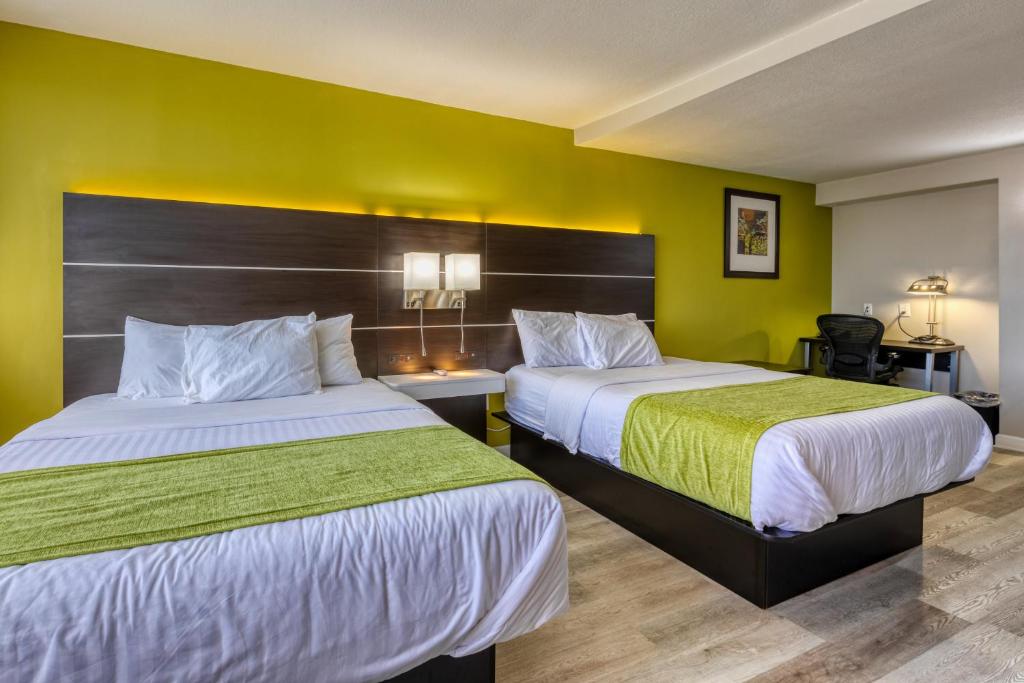 two beds in a hotel room with green walls at Hotel Weston in Marietta