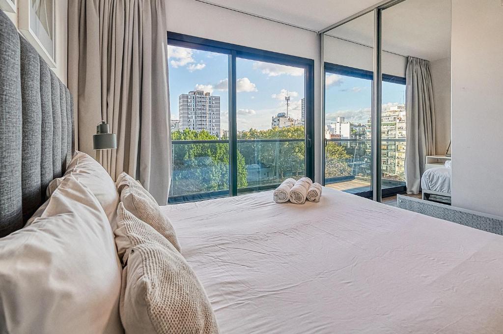 Un dormitorio con una cama blanca con una ventana grande. en Live Soho Boutique Apartments Belgrano, en Buenos Aires