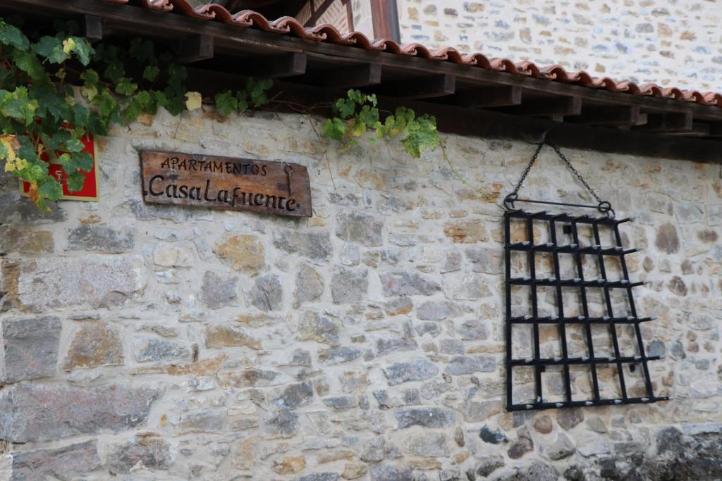 um sinal no lado de uma parede de pedra com uma grade de ferro em Apartamentos Rurales Casa Lafuente em Luquiano