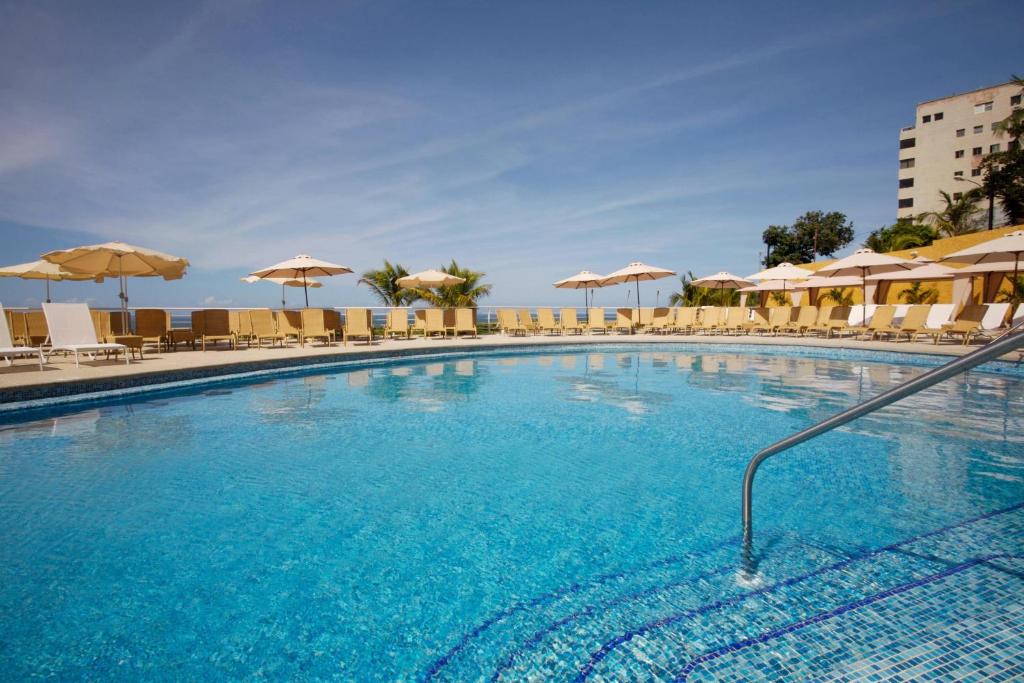 una gran piscina con sillas y sombrillas en Marriott Venezuela Hotel Playa Grande, en Playa Grande