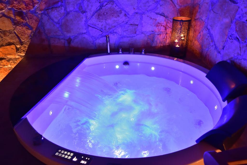 uma banheira de hidromassagem num quarto com uma parede roxa em SPA SUITE SICILIA em Rosolini