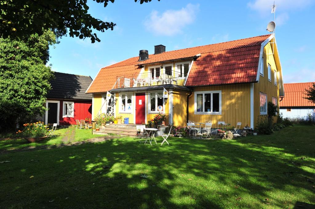 ein gelbes Haus mit rotem Dach und einem Hof in der Unterkunft STF Hagaby/Lantgården Hostel in Löttorp