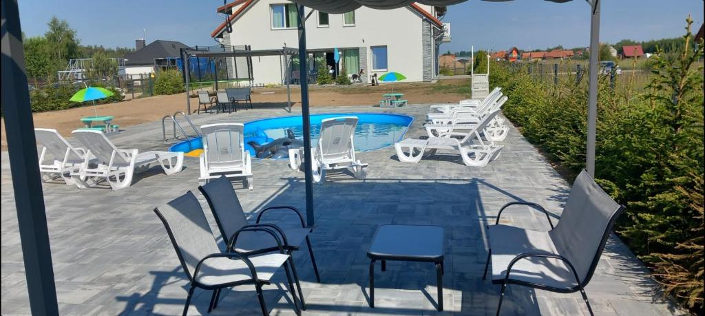 um grupo de cadeiras e uma piscina em Mazurskie Wzgórze BIS z basenem.3i4 em Rydzewo