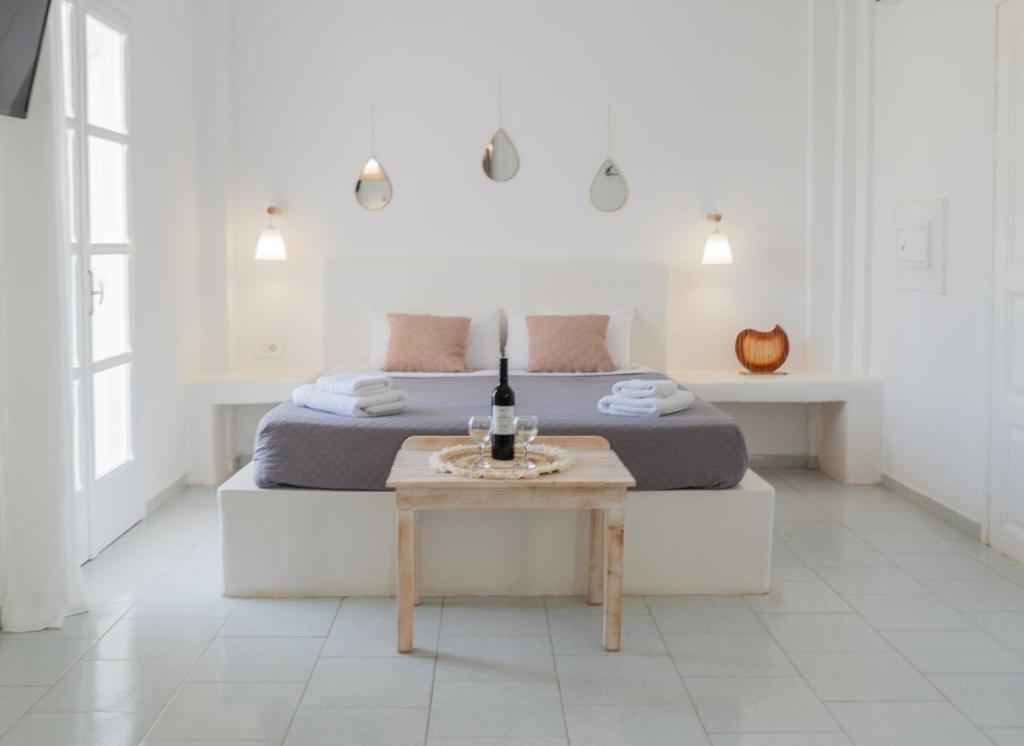 a white bedroom with a bed and a table at Sfiga villas in Perissa