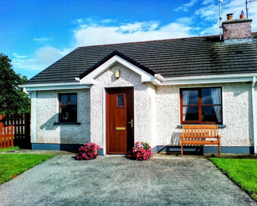 Casa blanca con puerta de madera y banco en Wild Atlantic Haven, cosy home nr. Ballina & Beach 