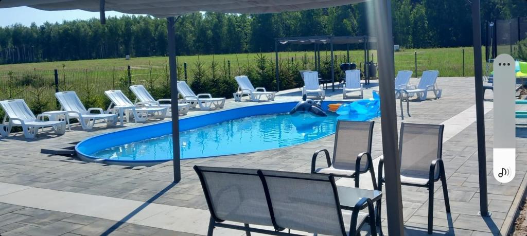 uma piscina com cadeiras e um guarda-sol em Mazurskie Wzgórze BIS z basenem em Rydzewo