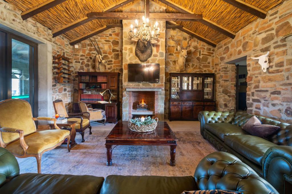 a living room with leather furniture and a stone wall at Kamagu Safari Lodge in Touwsrivier