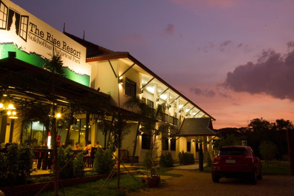 um edifício com um carro estacionado em frente em The Rise Resort em Sukhothai
