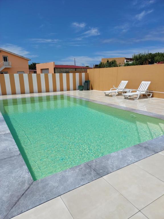 a swimming pool with two lounge chairs on a patio at O Cantinho do Sol in Lourinhã