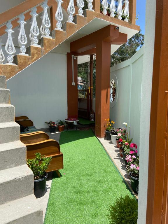 um pequeno jardim com relva debaixo de uma escada em DPM HOMESTAY em Bomdila