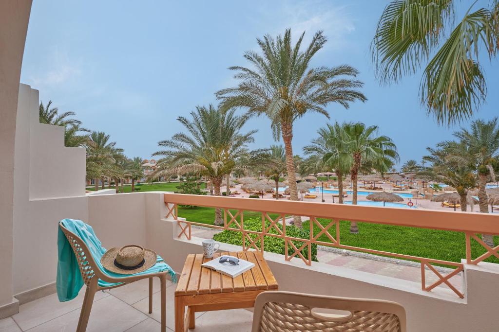 a balcony with a table and chairs and palm trees at Three Corners Sea Beach Resort in Coraya Bay