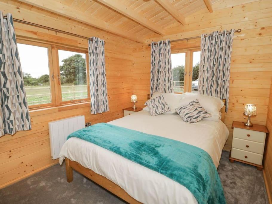 a bedroom with a bed in a log cabin at Ty Presto, Parc Y Fronwen in Newborough