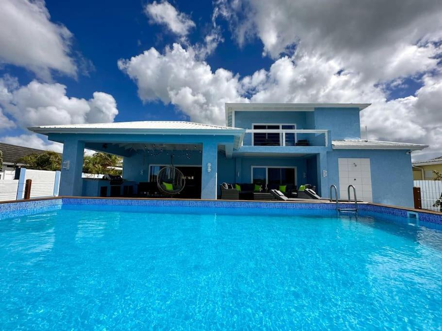 a blue house with a large swimming pool at Blue Haven in Jolly Harbour
