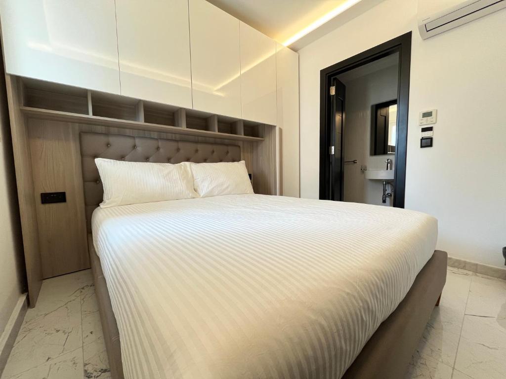 um quarto com uma cama grande e lençóis brancos em Msida Marina Apartments em Msida