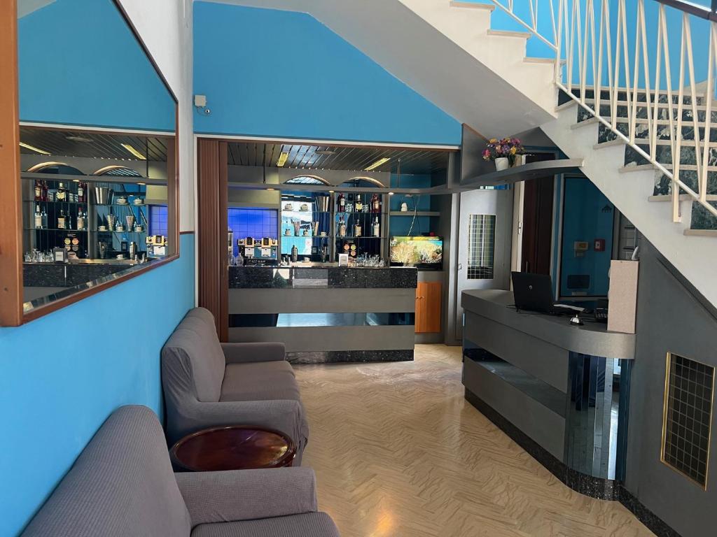 een lobby met een bar met een trap en stoelen bij Hotel Estense in Rimini