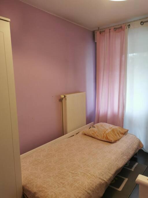 a bedroom with a bed with a pink wall at appartement cosy à 10 min du centre de Strasbourg in Strasbourg