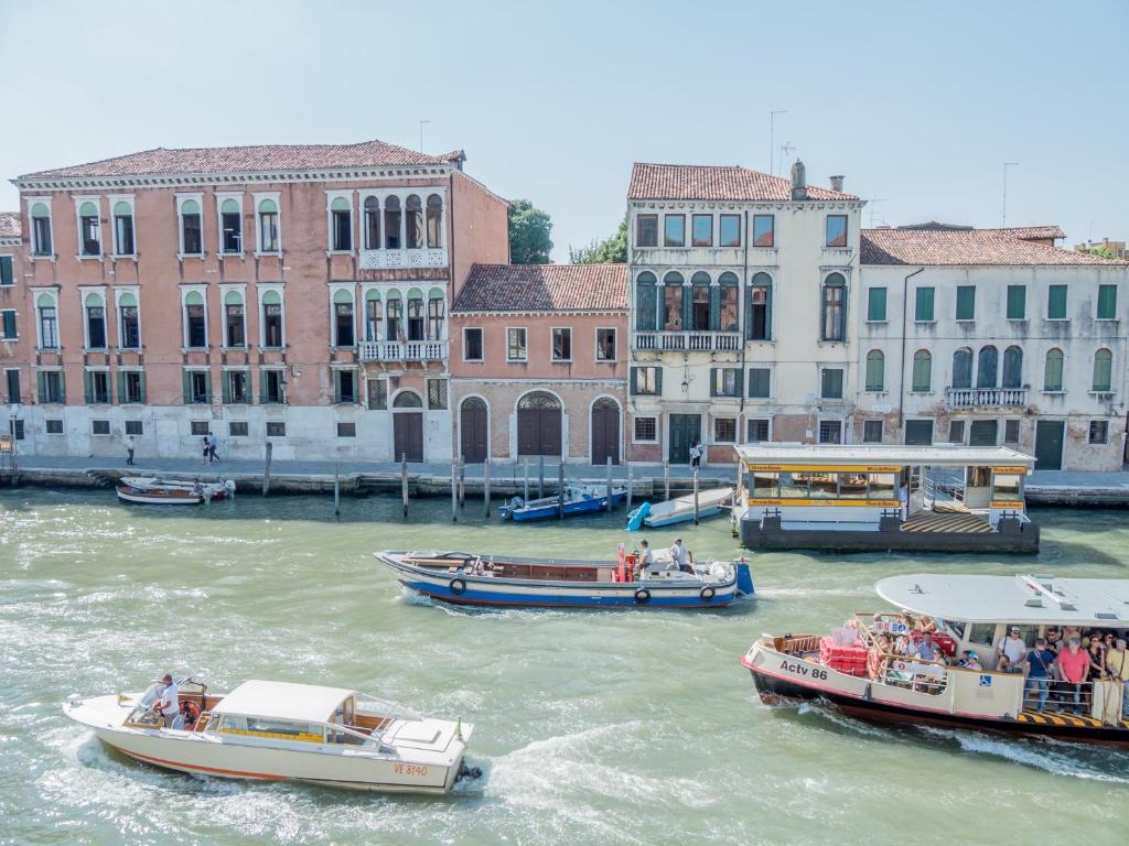 a group of boats in a river with buildings at Palace Canal View by Wonderful Italy in Venice