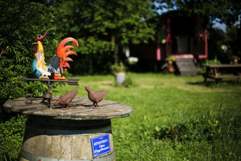 a bird bath with a statue of a rooster and three birds at la Pangée roulottes hébergement insolites in Lansac