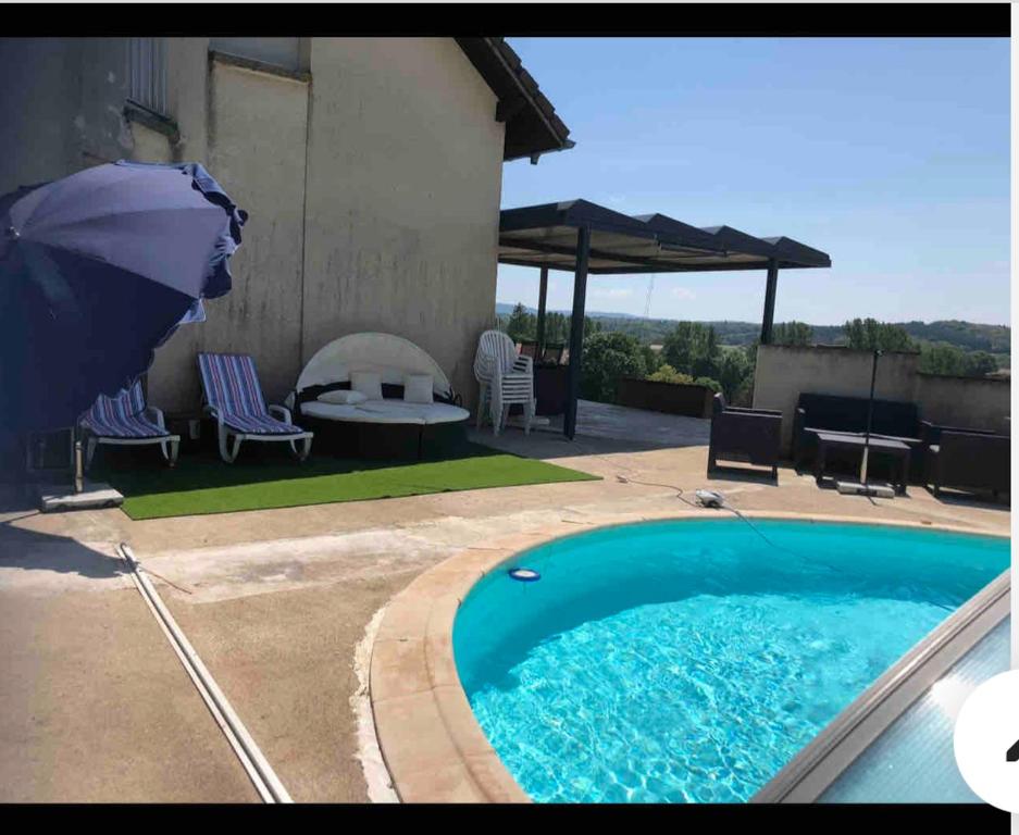 a swimming pool with a table and chairs and an umbrella at Chambres d hôtes 