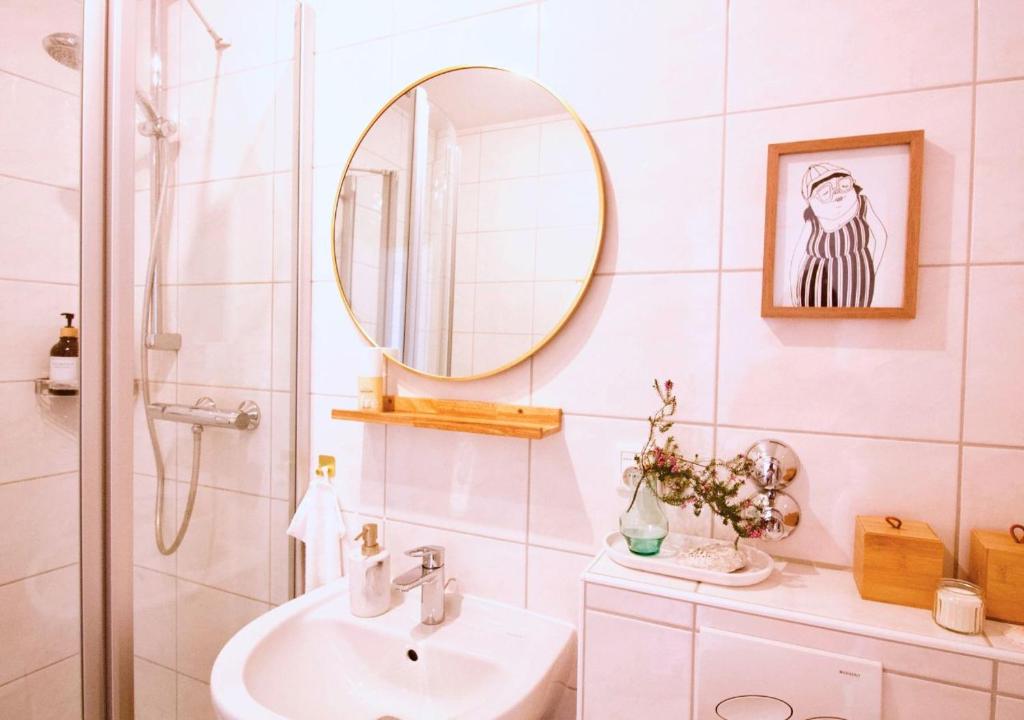 ein weißes Badezimmer mit einem Waschbecken und einem Spiegel in der Unterkunft Apartment mit Balkon - Netflix - nahe Messe Düsseldorf in Krefeld