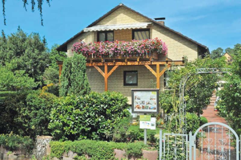 una casa con un balcón con flores. en Ferienwohnungen Haus Bahlo en Bad Bevensen