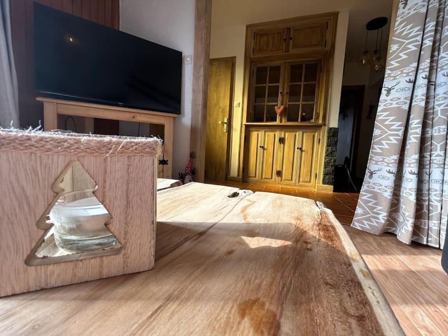 a room with a wooden floor with a tv and a box at Le Repère des Quatre Dubois in Le Tholy